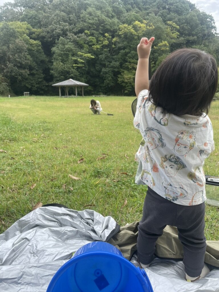 屋外で立って遠くを指さす1歳児