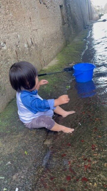 浅い水辺に座る1歳児