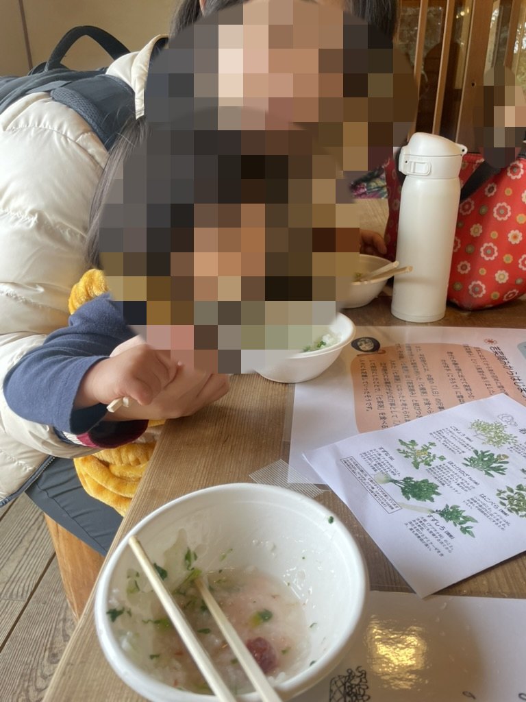 里山の行事で七草粥を食べる親子