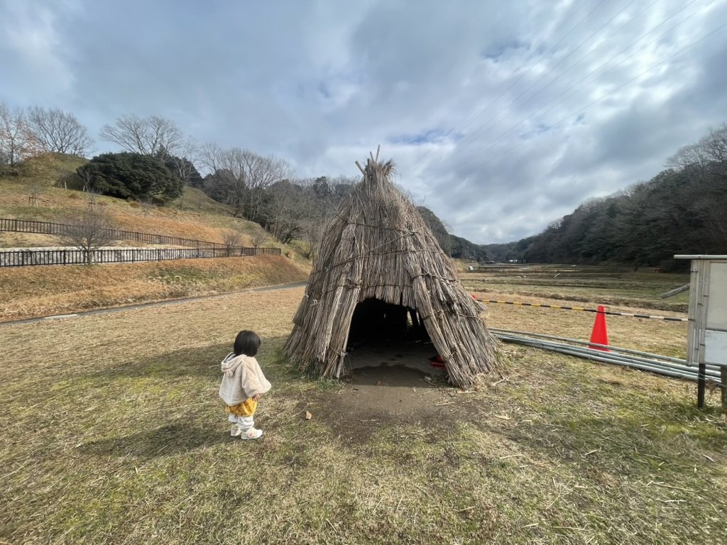 里山のわらの小屋へ近づく1歳児