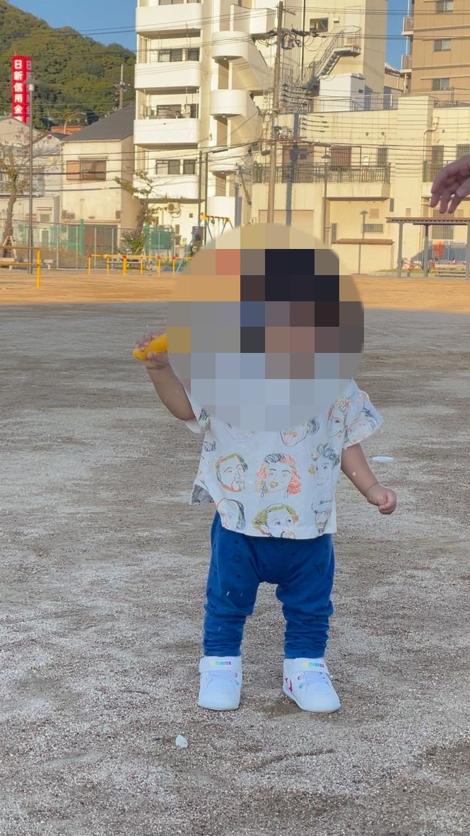 広場でシャボン玉を持って遊ぶ1歳児