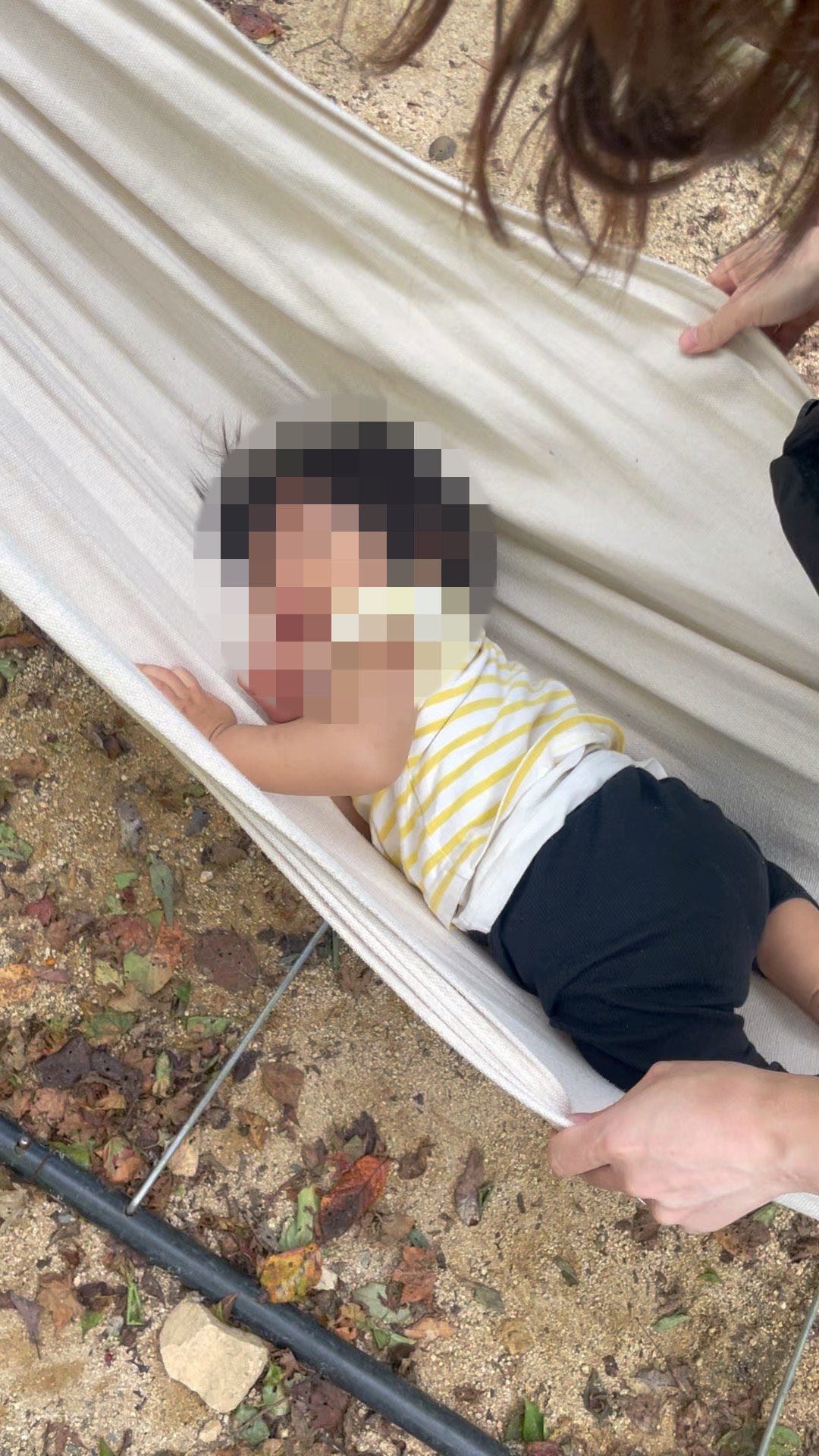 屋外のハンモックに寝転ぶ1歳児