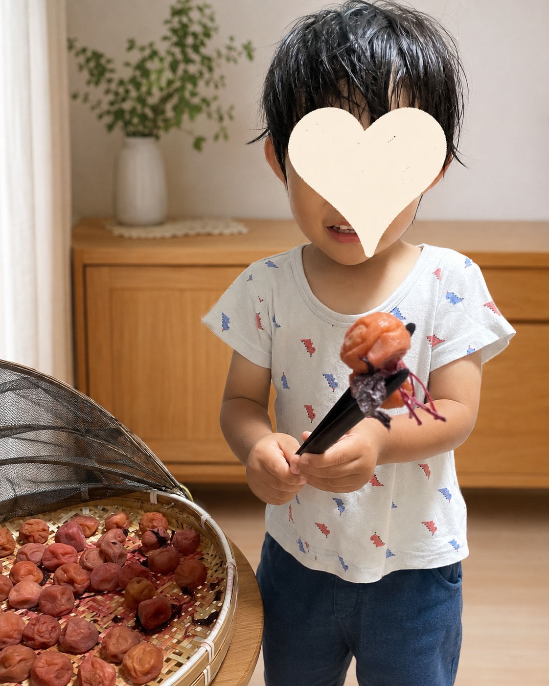 完成に近づいた梅と赤しそをトングで持って見せる2歳児