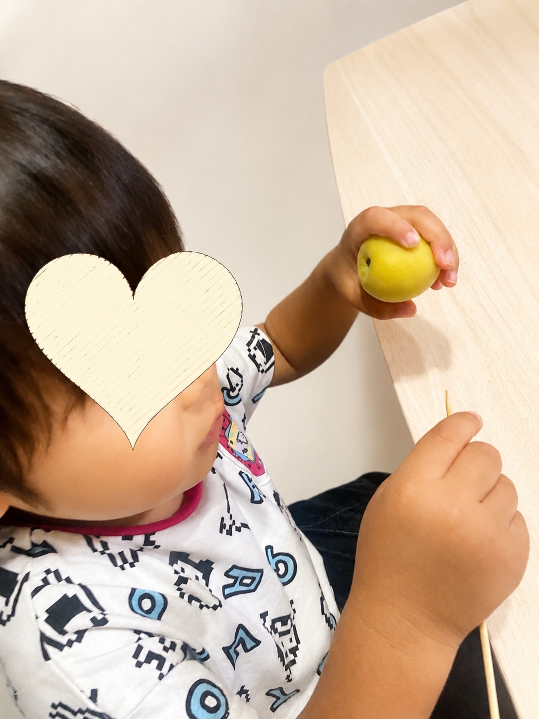 2歳児が竹串で梅のヘタ取りに挑戦している様子